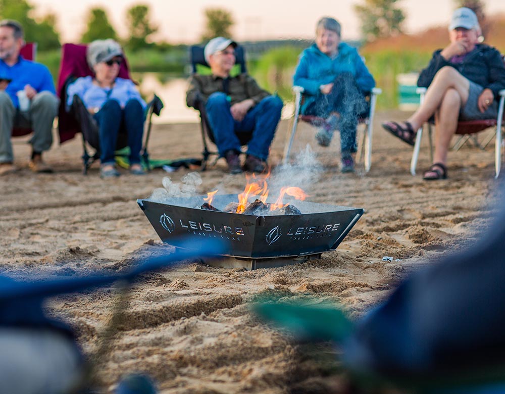 people sit around a campfire on the beach