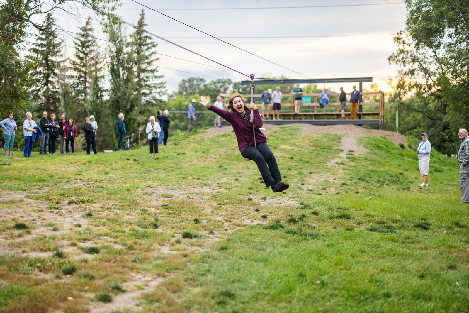 A women smiles at the camera while riding the zipline