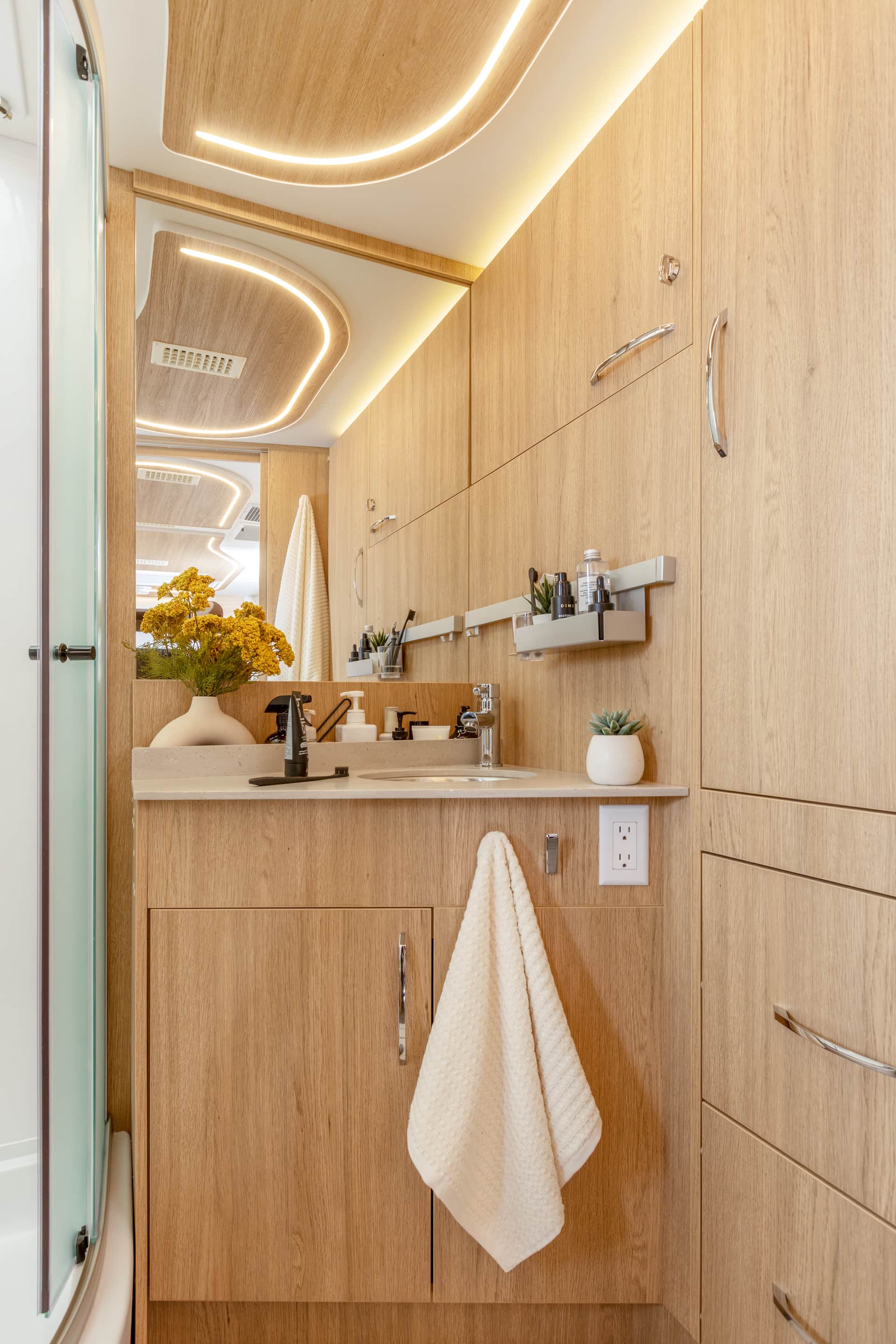Unity Murphy Bed Lounge shown with Rift Oak cabinetry, Crystal White cabinetry upgrade, Concrete countertops, and Sand upholstery.