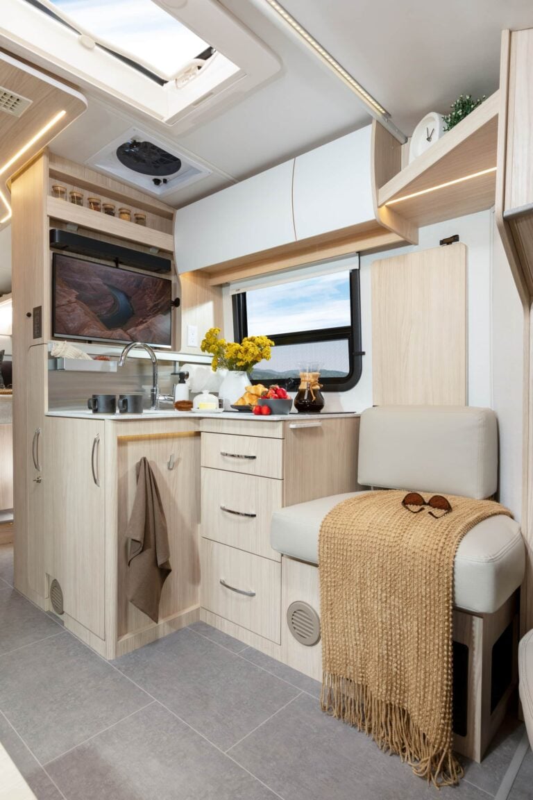 Wonder Rear Twin Bed shown with White Oak cabinetry, Crystal White cabinetry upgrade, Mineral countertops, and Sand upholstery.