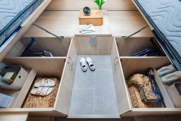 Wonder Rear Twin Bed shown with White Oak cabinetry, Crystal White cabinetry upgrade, Mineral countertops, and Sand upholstery.
